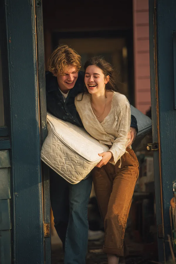 Two friends carrying a new mattress into an apartment doorway